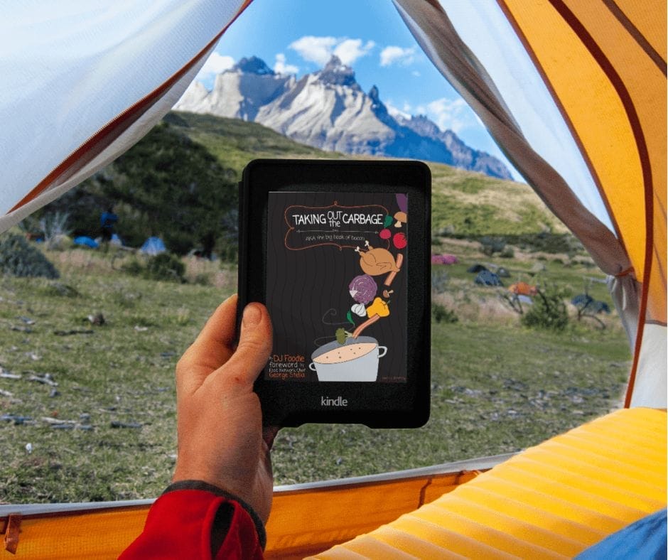 Taking Out the Carbage: AKA the Big Book of Bacon Person holding the Taking Out the Carbage eBook on a tablet while relaxing in a tent with a mountain view in the background.