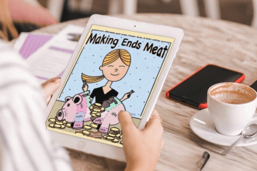 Hands holding a tablet displaying the Making Ends Meat cookbook cover; a low-carb batch cooking and freezer meal guide.